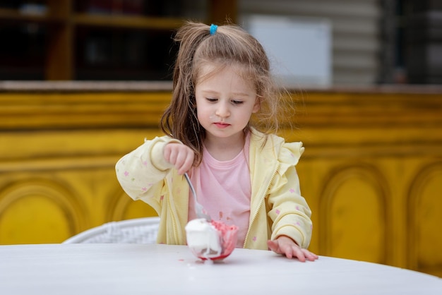 Una niña está comiendo helado y tiene una cuchara en la mano.