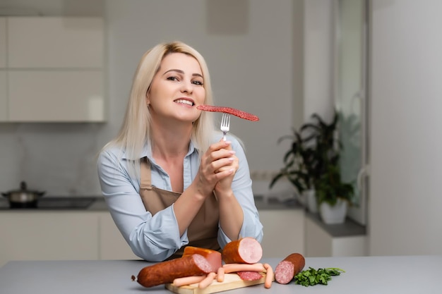 La niña está comiendo salchichas. Un trozo de salchicha. Sonrisa y Alegría. El concepto de negocio es el atractivo de la marca. Apetito