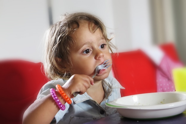 Niña está comiendo con un tenedor