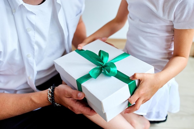 La niña le está dando a su apuesto padre una caja de regalo el día del padre