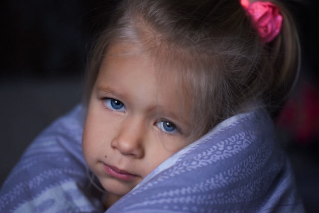 La niña está enferma y toma el sol en la cama.