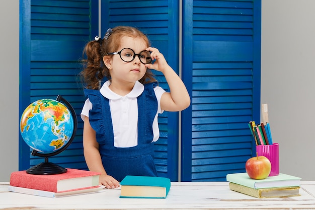 La niña está estudiando mientras usa un gorro de graduación