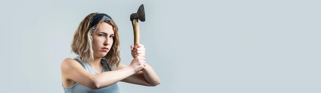 La niña está furiosa con una foto de estudio de hacha sobre un fondo gris El concepto de violencia doméstica igualdad de género