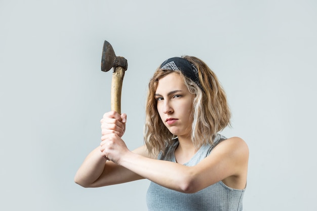 La niña está furiosa con una foto de estudio de hacha sobre un fondo gris El concepto de violencia doméstica