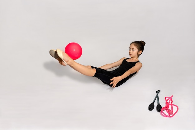 Niña está haciendo ejercicio con pelota en el piso