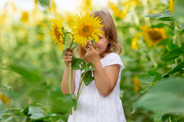 Una niña está jugando con flores de girasol en un campo con girasoles
