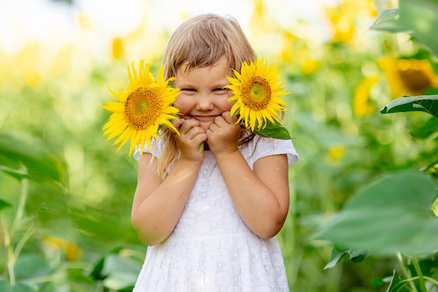 Una niña está jugando con flores de girasol en un campo con girasoles