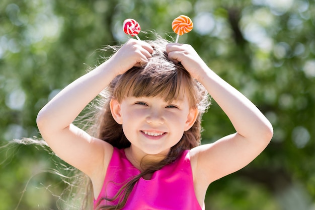 La niña está jugando con grandes dulces en un palo.