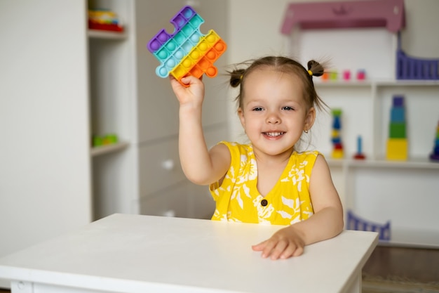 Una niña está jugando en una mesa con un juguete popit.