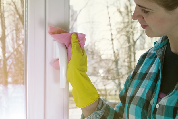 La niña está limpiando la casa, limpiando las ventanas.