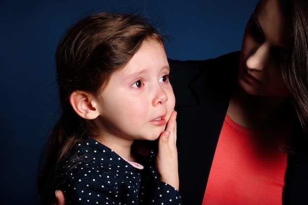 La niña está molesta y llora de resentimiento en los brazos de su madre.