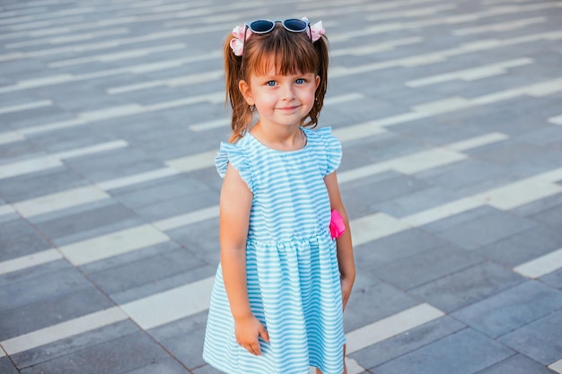 Una niña está de pie con gafas de sol Protección de la luz solar Entretenimiento y mimos del niño