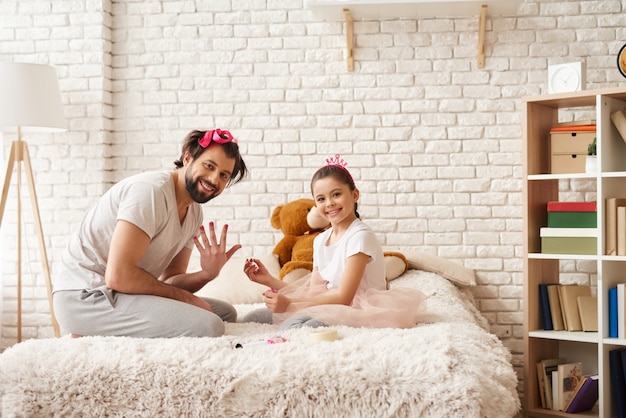 Niña está pintando papás uñas con un esmalte.