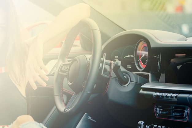 La niña está sentada al volante de un automóvil. Interior de cuero negro de un coche moderno.