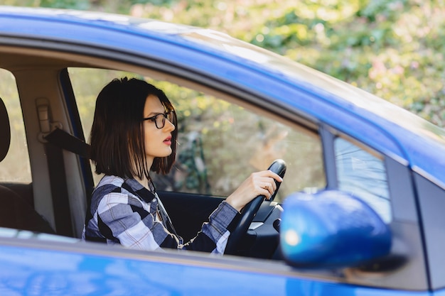 La niña está sentada al volante del coche.