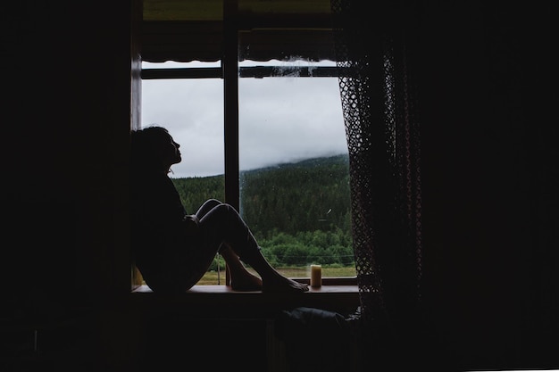 La niña está sentada en el alféizar de la ventana.