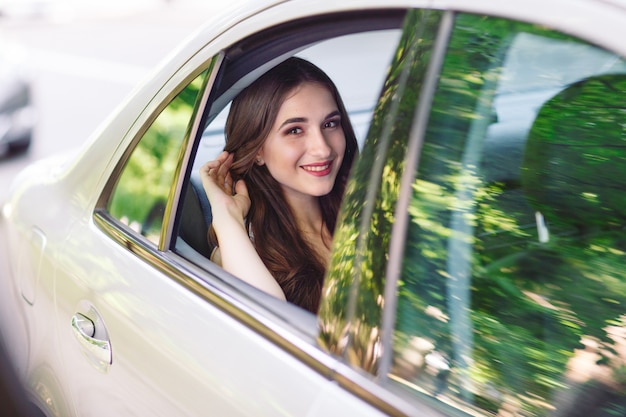 La niña está sentada en el asiento trasero del automóvil.