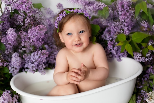 una niña está sentada en el baño. bañándose en un baño con flores