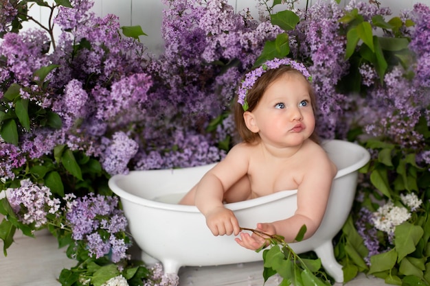 una niña está sentada en el baño. bañándose en un baño con flores