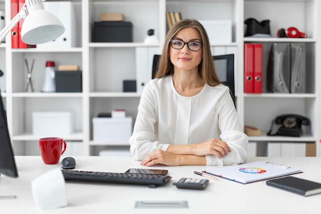 Una niña está sentada en el escritorio de la computadora en la oficina.