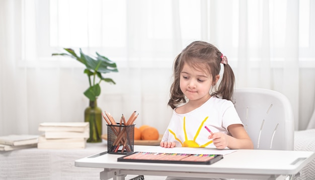 La niña está sentada a la mesa y haciendo los deberes. El niño aprende en casa. Concepto de educación en casa.