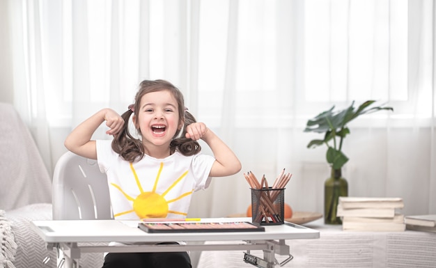 La niña está sentada a la mesa y haciendo los deberes. El niño aprende en casa. Concepto de educación en casa.