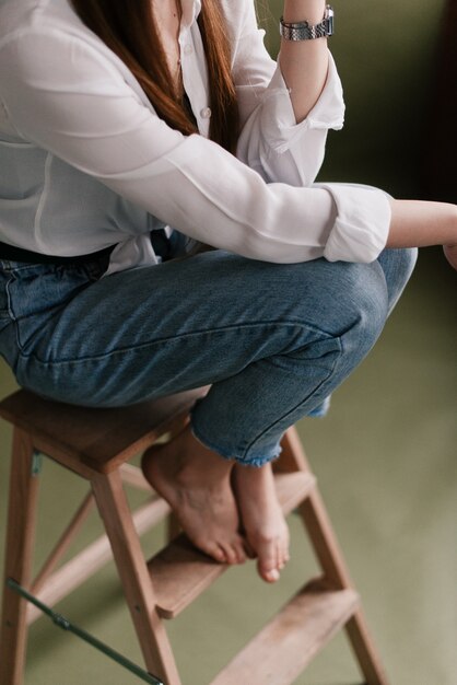 La niña está sentada con las piernas cruzadas. Rodillas de mujer. Concepto de espera y relajación, estilo de color Vintage.