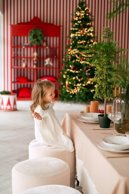 Una niña está sentada en la sala de estar en una mesa festiva en Nochebuena