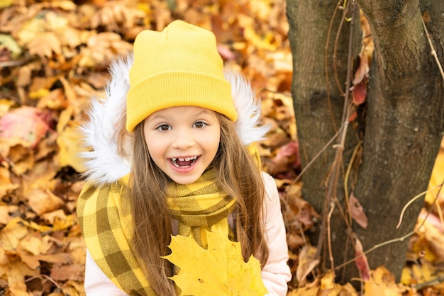 Una niña está sentada en el suelo en el bosque de otoño.