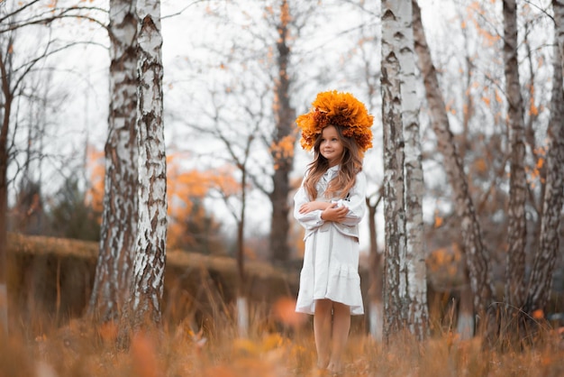 Una niña está sola en el bosque de otoño.