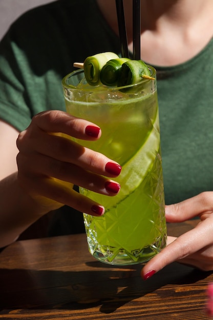 La niña está sosteniendo un cóctel alcohólico con pepino closeup