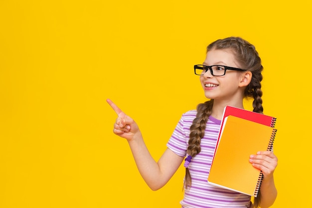 La niña está sosteniendo un libro y mirando hacia otro lado Linda niña sobre fondo amarillo aislado