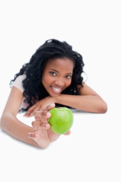 Una niña está sosteniendo una manzana verde frente a ella