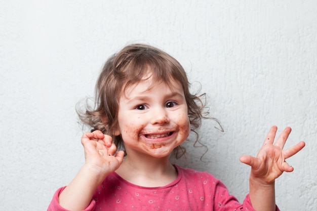 La niña está sucia de chocolate. Cara graciosa