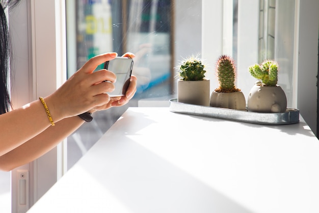 La niña está tomando un cactus en una cafetería, hipster.