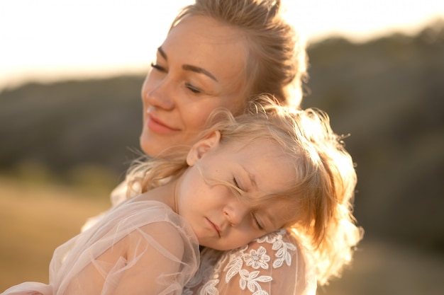 La niña está tomando el sol y durmiendo en el hombro de su madre