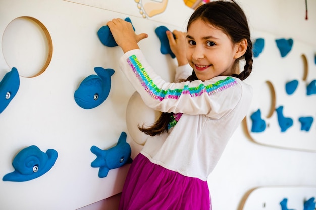 La niña está trepando en la pared de la sala de juegos.