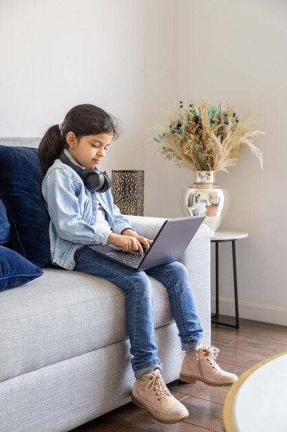 Niña está usando su computadora portátil en la sala de estar