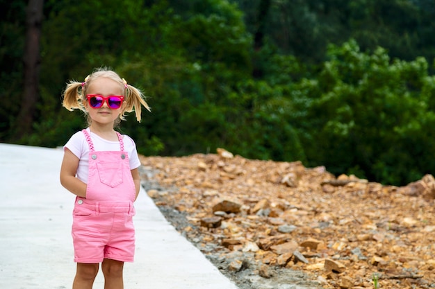 Niña con estilo con el pelo rubio que se coloca al aire libre