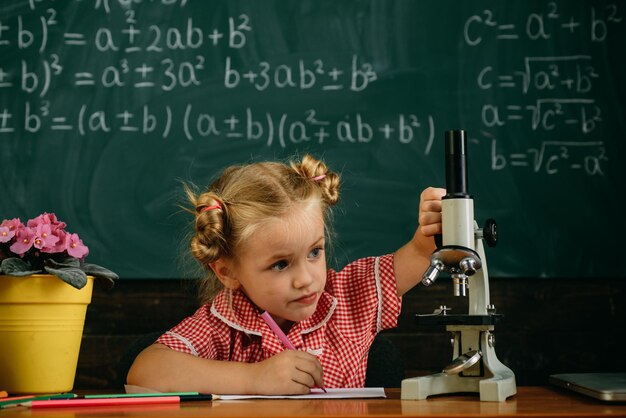 Niña estudia en el aula de biología en la escuela Colegiala trabaja en investigación biológica con microscopio