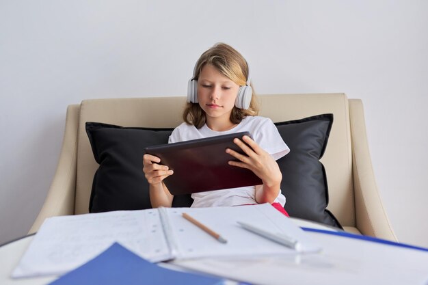 Niña estudia en línea en casa niño con tableta digital en auriculares