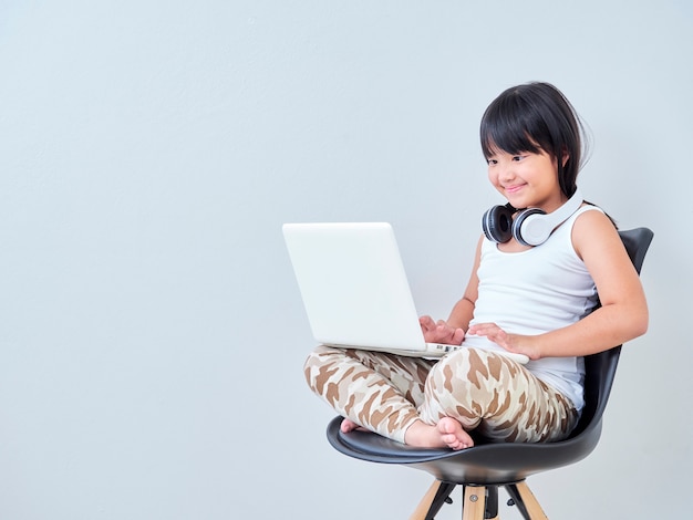 La niña estudia en línea con la computadora portátil.