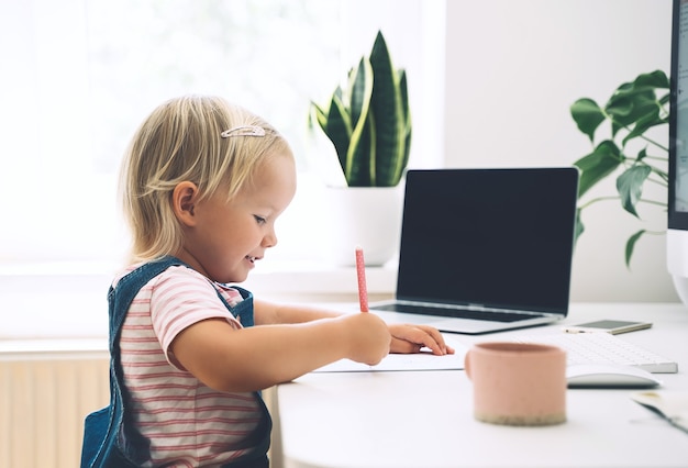 Niña estudiando y dibujando en el escritorio Aprendizaje en línea para niños