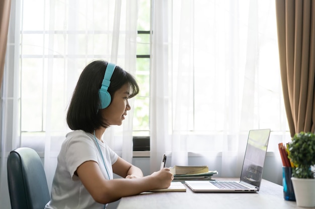Niña estudiando en línea en la computadora portátil en casa