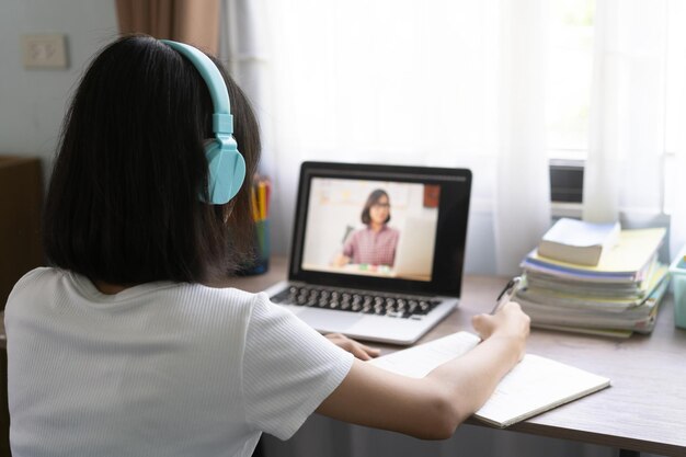 Foto niña estudiando en línea en la computadora portátil en casa