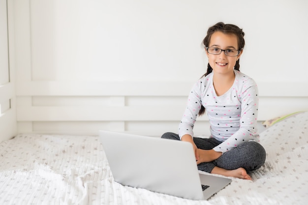 Niña estudiando en línea usando su computadora portátil en casa