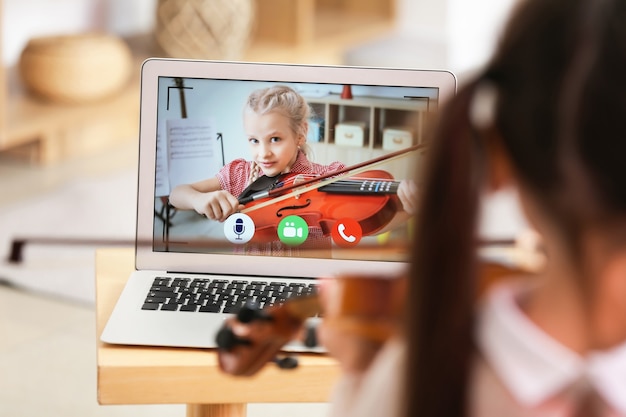 Niña estudiando música con su amiga en línea en casa