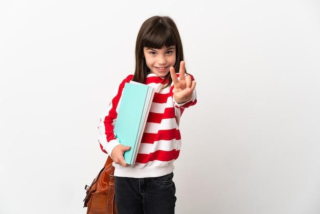 Foto niña estudiante aislada en la pared blanca sonriendo y mostrando el signo de la victoria