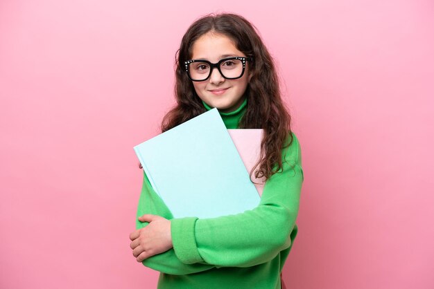 Niña estudiante aislada sobre fondo rosa sonriendo mucho