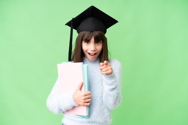 Niña estudiante caucásica sobre un fondo aislado sorprendida y apuntando al frente